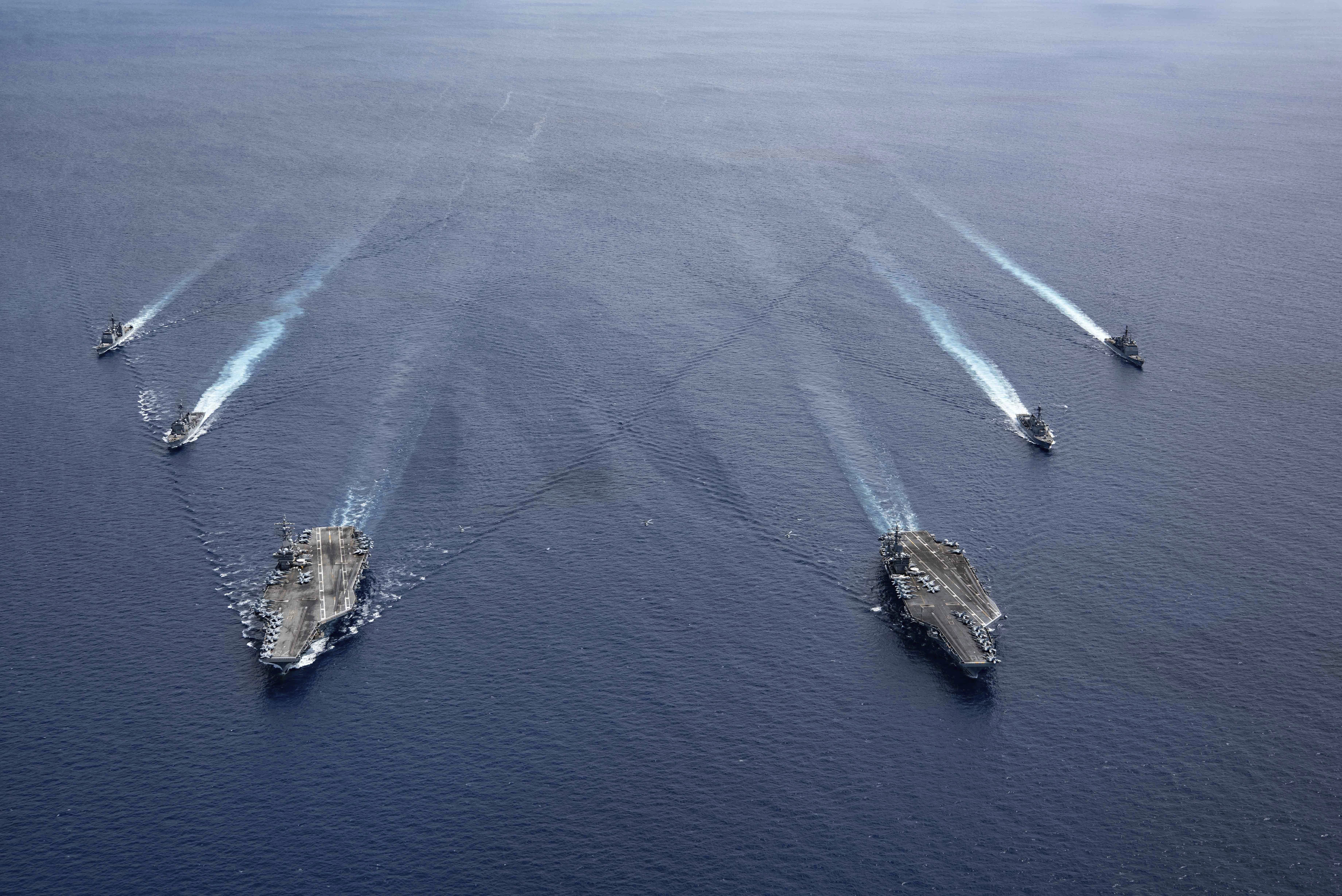 In this photo provided by U.S. Navy, the U.S.S. Ronald Reagan (CVN 76) and U.S.S. Nimitz (CVN 68) Carrier Strike Groups steam in formation, in the South China Sea, Monday, July 6, 2020.